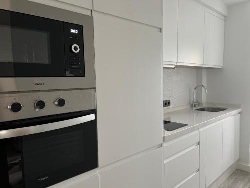 a kitchen with white cabinets and a microwave at Rotonda del Minotauro Apartamento Turístico AT-CC-00674 in Coria