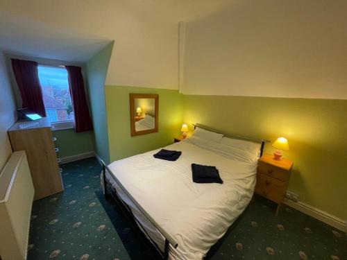 a bedroom with a bed with two black towels on it at 2 Bedroom Holiday Apartment Skegness - Flat 17 in Skegness