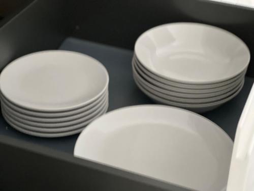 three white plates and bowls sitting in a drawer at Rotonda del Minotauro Apartamento Turístico AT-CC-00674 in Coria