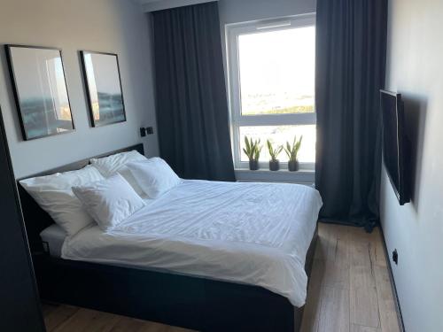 una camera da letto con un letto con lenzuola bianche e una finestra di Apartament Comfort 10 a Danzica