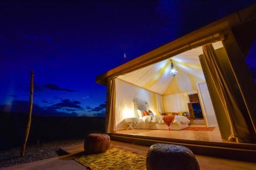 a view of a bed in a tent at night at Agafay Pearl Camp Marrakech in Marrakech