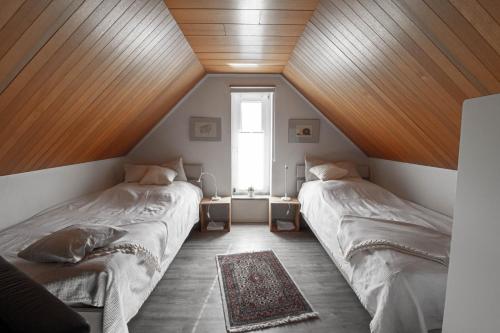 two beds in a room with wooden ceilings at Lütt Hus Erna in Fehmarn