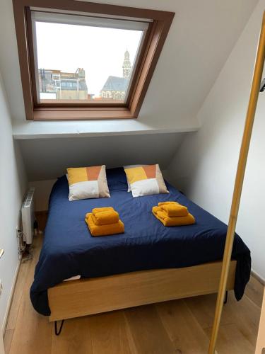 een slaapkamer met een bed met gele kussens en een raam bij Antwerpcityhome in Antwerpen