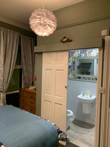 a bedroom with a bed and a bathroom with a sink at CornerHouse Guesthouse in Penrith