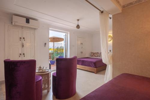 a bedroom with purple chairs and a bed and a window at Riad Kech Soul Boutique & Spa in Marrakech