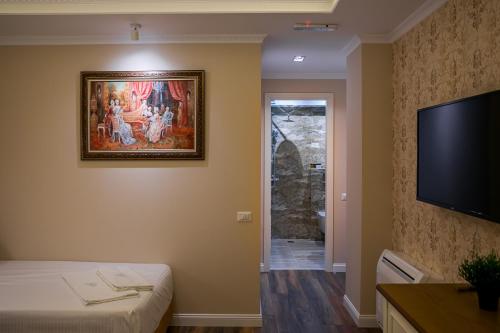 a room with a painting on the wall and a flat screen tv at Legacy Boutique Hotel in Korçë