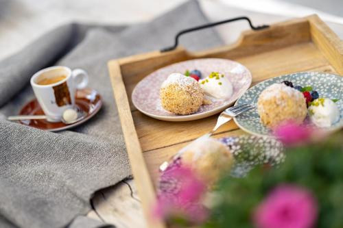 a tray with two plates of desserts and a cup of coffee at Gästehaus Alte Bergmühle in Fischbachau