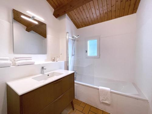 een badkamer met een wastafel, een bad en een spiegel bij Le Parc des Mimosas in Noirmoutier-en-l'lle
