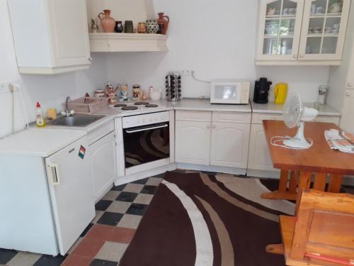 een keuken met witte kasten, een wastafel en een vaatwasser bij Bella Apartman in Sárospatak