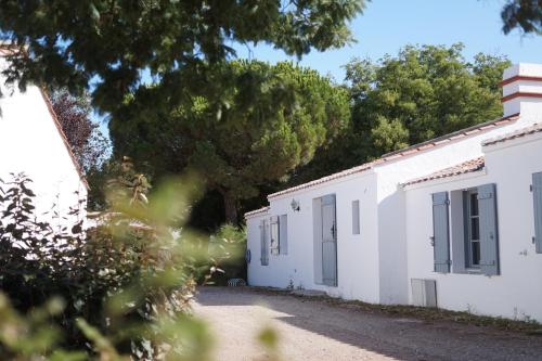 a couple of white buildings with trees in the background at Le Parc des Mimosas in Noirmoutier-en-l'lle