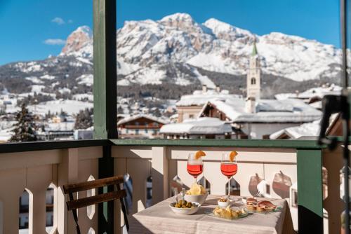 - une table avec de la nourriture et des verres à vin sur un balcon avec des montagnes dans l'établissement Parc Hotel Victoria, à Cortina dʼAmpezzo