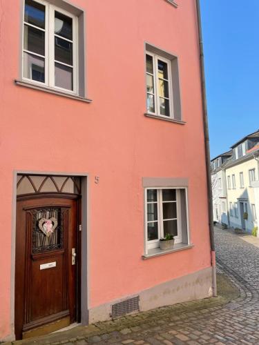 a pink building with a door and two windows at Uriges Ferienhaus in der Altstadt von Saarburg mit Sauna, Kinderspielecke, 1000Mbit Wlan, 1 Minute vom Wasserfall entfernt in Saarburg