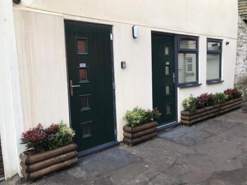 a green door on a house with two potted plants at Jacob’s Ally in Knaresborough