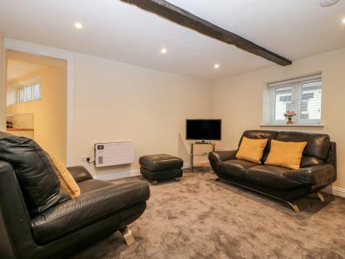 sala de estar con muebles de cuero y TV de pantalla plana en Jacob’s Ally en Knaresborough