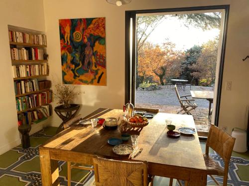 a wooden table in a room with a large window at La maison de Mado et sa cabane dans les arbres in Plan dʼAups