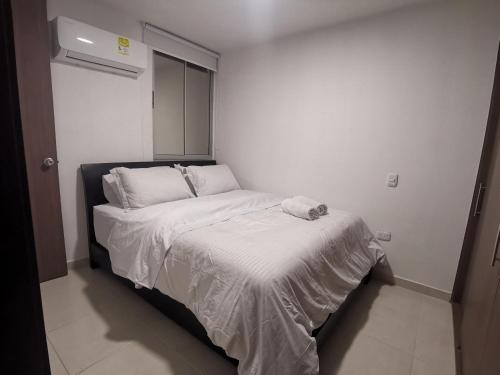 a bed in a small room with a white bedspread at Hermoso Apartamento Zona Norte Miramar # in Barranquilla