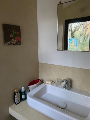 un lavabo blanc dans une salle de bain avec un miroir dans l'établissement La maison de Mado et sa cabane dans les arbres, à Plan dʼAups