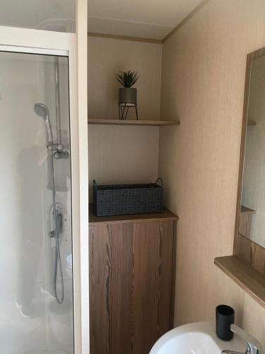 a bathroom with a shower and a sink and a sink at Haggerston Castle 6 Berth Caravan - Lakeside North 23 in Cheswick