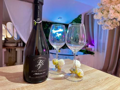 une bouteille de vin et deux verres à vin sur une table dans l'établissement Romantica Spa, à Saint-Dié-des-Vosges