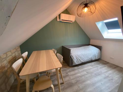Cette chambre mansardée comprend une table et un lit. dans l'établissement Logement Loire climatisé, La Halte de Cuze, aux abords de la Loire a vélo, à Huismes