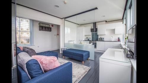 ein Wohnzimmer mit einem blauen Sofa und einer Küche in der Unterkunft Luxury Penthouse in listed building in Newcastle upon Tyne