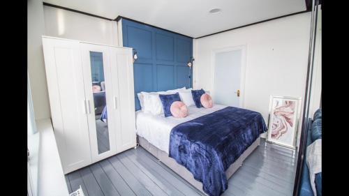 1 dormitorio con 1 cama con paredes azules y espejo en Luxury Penthouse in listed building, en Newcastle
