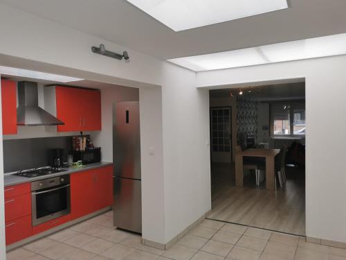 La cuisine est équipée de placards rouges et d'un réfrigérateur en acier inoxydable. dans l'établissement La cosy house Tourcoing, à Tourcoing