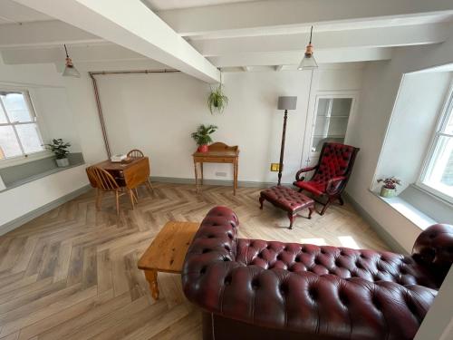 a living room with a leather couch and a table at Peaceful period cottage in central location in Penzance
