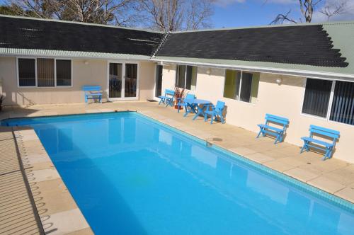a swimming pool with blue chairs and a house at Bambra Reef Lodge in Sandford