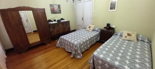 a bedroom with two beds and a mirror and wooden floors at EL BORDON DE LA CASA BATALLON in Sarria