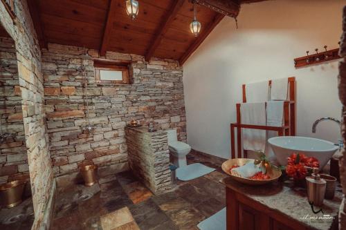 uma casa de banho com um lavatório e uma parede de tijolos em Itmenaan Estate in the Himalayas em Almora