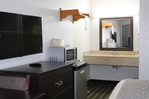a hotel room with a bed and a sink and a television at Savannah Inn - Savannah I-95 North in Port Wentworth