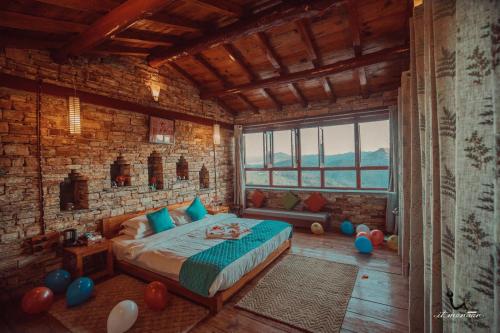 a bedroom with a bed and a brick wall at Itmenaan Estate in the Himalayas in Almora