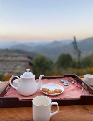 a tea set on a tray with a tea pot and cups at Itmenaan Estate in the Himalayas in Almora