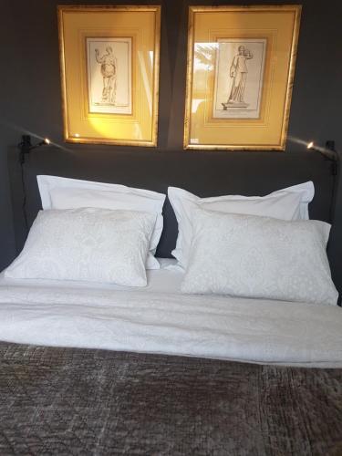 een bed met witte kussens en twee foto's aan de muur bij B&B Joke de Groot in Maastricht