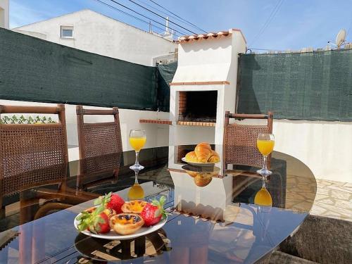a table with a bowl of fruit and two glasses of wine at Private Villa 4 BR&patio - 3 mins from Beach&Surf in Baleal