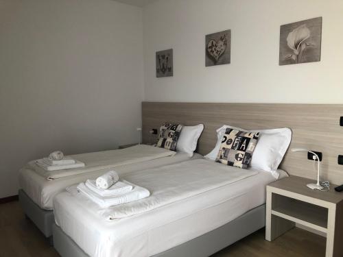 1 Schlafzimmer mit 2 Betten mit weißer Bettwäsche und Kissen in der Unterkunft HOME NUOVA OSTIGLIA in Padernello