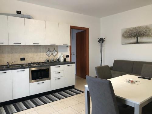 eine Küche mit weißen Schränken, einem Tisch und einer Couch in der Unterkunft HOME NUOVA OSTIGLIA in Padernello