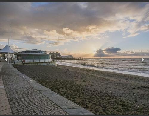 uma praia arenosa com um cais e o oceano em Cranwell Court Apartments em Aberystwyth