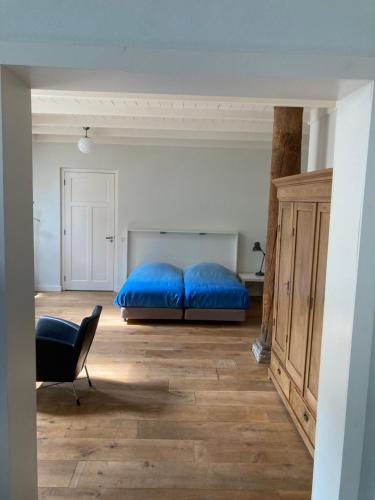 1 dormitorio con 1 cama azul y 1 silla en Duerswald, en Wijnjewoude