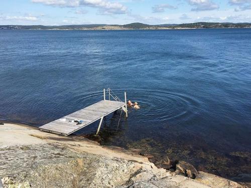 a couple of people swimming on a dock in the water at 6 person holiday home in Höviksnäs-By Traum in Höviksnäs