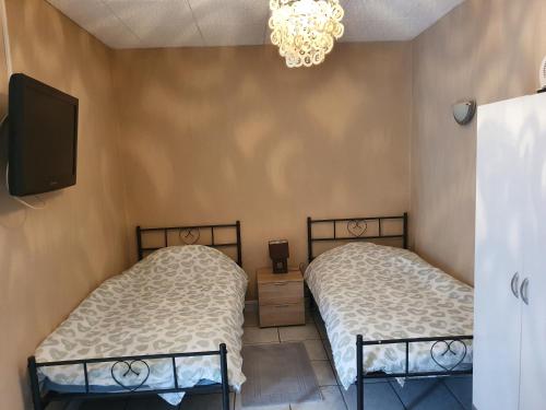 two twin beds in a room with a tv at Appartement F1 rez de chausser BG N°2 in Bains-les-Bains