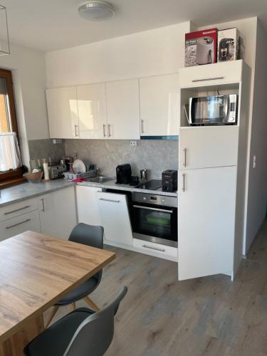 シオーフォクにあるSiófok VIP apartmanのキッチン(木製テーブル、白い冷蔵庫付)