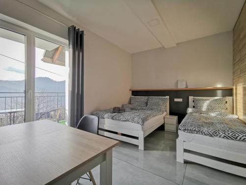a bedroom with two beds and a table and a balcony at Widokowy Szczawnica in Szczawnica