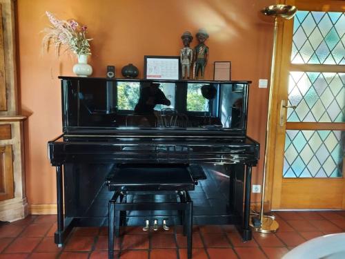 a black piano with a stool in a room at Au Clos Caleste in Wellin
