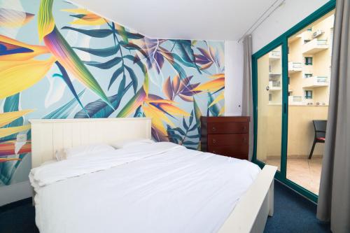 a bedroom with a white bed and a colorful mural at Sea Of Galilee 2Bdrm Apartments in Tiberias - דירות 2 חדרי שינה וסלון עם נוף לכנרת בטבריה in Tiberias