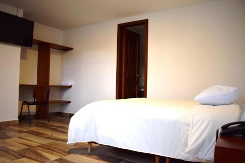 um quarto com uma cama branca e piso em madeira em Hotel Villa Isabel em Pasto