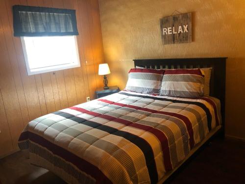 a bedroom with a bed with a striped comforter and a window at High Country Lodge in Alto