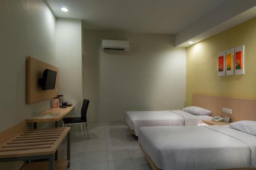 una camera d'albergo con due letti e un tavolo con sedie di Hotel Quirin a Semarang
