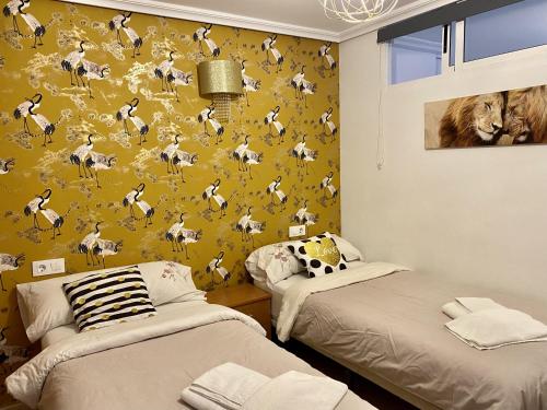 Duas camas num quarto com papel de parede amarelo em MY SUNNY PAYMA BEACH Apartment em Benidorm